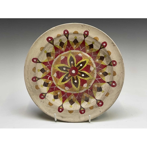 832 - A studio pottery unglazed plate, painted with a geometric floral design, the back indistinctly signe... 