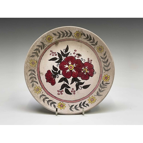 832 - A studio pottery unglazed plate, painted with a geometric floral design, the back indistinctly signe... 