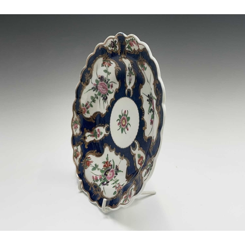 909 - A Worcester porcelain plate, circa 1770, the blue scale ground decorated with gilt edged floral pane... 