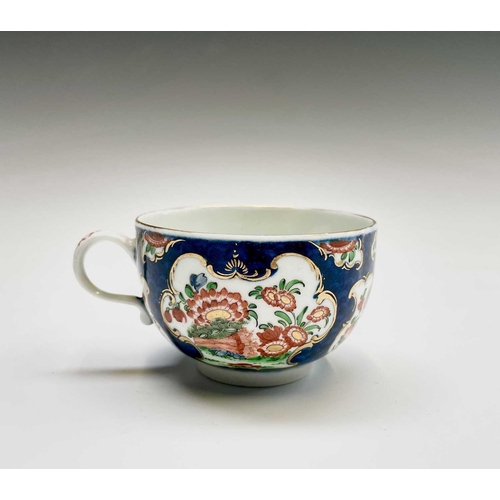 910 - A Worcester porcelain teacup and saucer, circa 1770, the blue scale ground decorated with panels of ... 