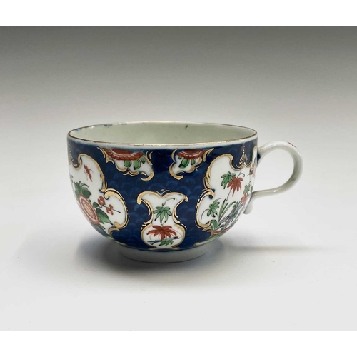 910 - A Worcester porcelain teacup and saucer, circa 1770, the blue scale ground decorated with panels of ... 