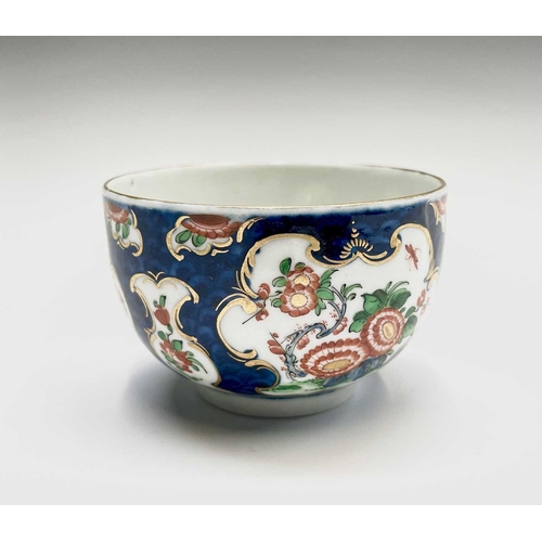 910 - A Worcester porcelain teacup and saucer, circa 1770, the blue scale ground decorated with panels of ... 