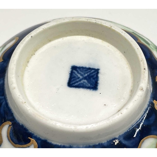 910 - A Worcester porcelain teacup and saucer, circa 1770, the blue scale ground decorated with panels of ... 