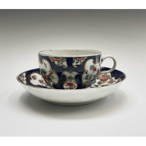 910 - A Worcester porcelain teacup and saucer, circa 1770, the blue scale ground decorated with panels of ... 