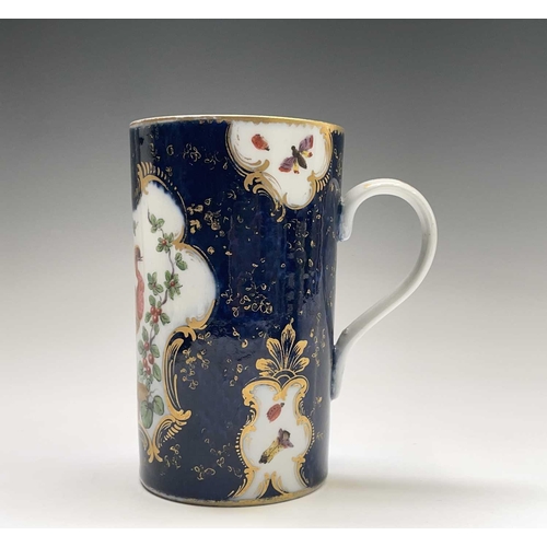 915 - A Continental porcelain mug, in the Worcester style, the blue scale ground with panels of an exotic ... 