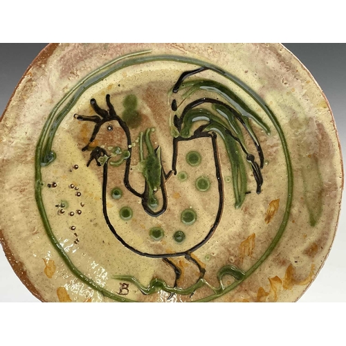 959 - A Ben Fosker (b.1960) slip decorated earthenware plate painted with a cockerel. Diameter 23.5cm.