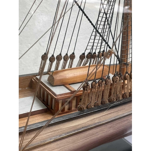 99 - A wooden model of the Cutty Sark, with stained hull and gilt detail, on a stand and contained in a g... 