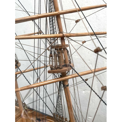 99 - A wooden model of the Cutty Sark, with stained hull and gilt detail, on a stand and contained in a g... 