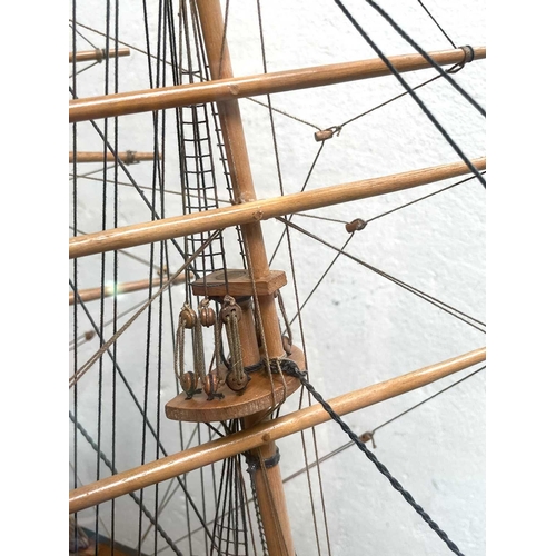 99 - A wooden model of the Cutty Sark, with stained hull and gilt detail, on a stand and contained in a g... 