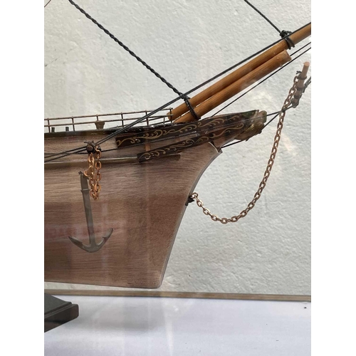 99 - A wooden model of the Cutty Sark, with stained hull and gilt detail, on a stand and contained in a g... 