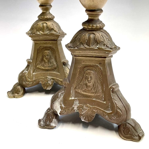 168 - A pair of brass candlesticks the tripod bases with religious imagery, height 38.5cm.