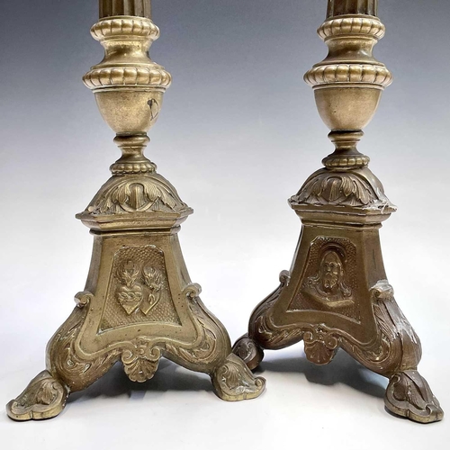 168 - A pair of brass candlesticks the tripod bases with religious imagery, height 38.5cm.