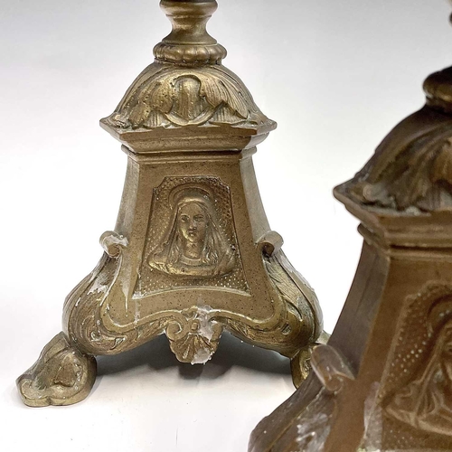 168 - A pair of brass candlesticks the tripod bases with religious imagery, height 38.5cm.