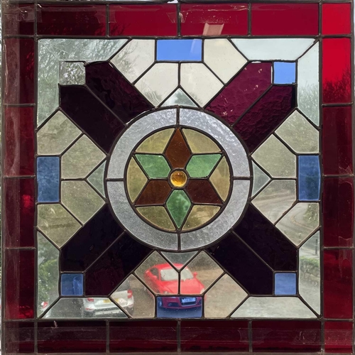 51 - A square stained glass panel with a symmetrical design, 51cm, and a pair of stained glass panels the... 