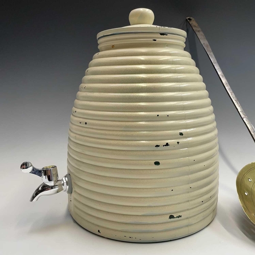 65 - A large glass honey bee skep shaped vessel with spigot and a brass cream skimmer, vessel height 31cm... 