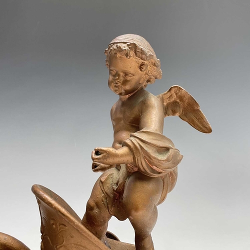 70 - A pair of late 19th/early 20th spelter figure groups, each modelled as a cherub standing in a chario... 