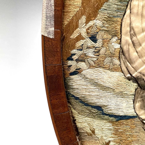 2803 - A Regency silk work oval picture of a shepherdess preparing a wreath, with painted detail, mahogany ... 
