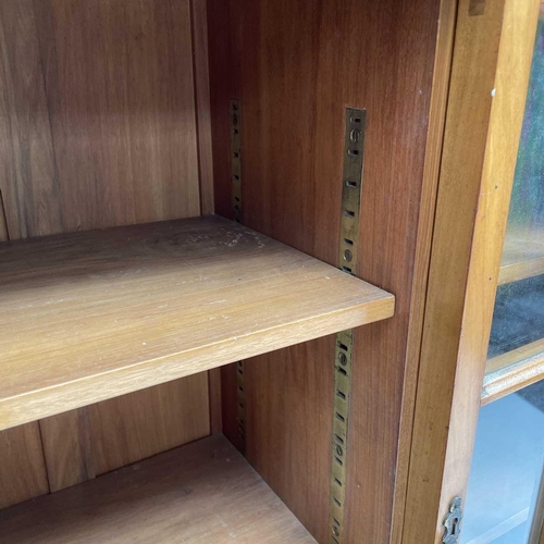 3002 - An Arts and crafts Cotswold school walnut glazed bookcase, the sycamore banded top with rounded corn... 