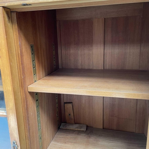 3002 - An Arts and crafts Cotswold school walnut glazed bookcase, the sycamore banded top with rounded corn... 