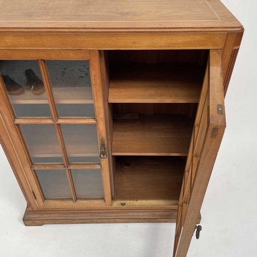 3002 - An Arts and crafts Cotswold school walnut glazed bookcase, the sycamore banded top with rounded corn... 