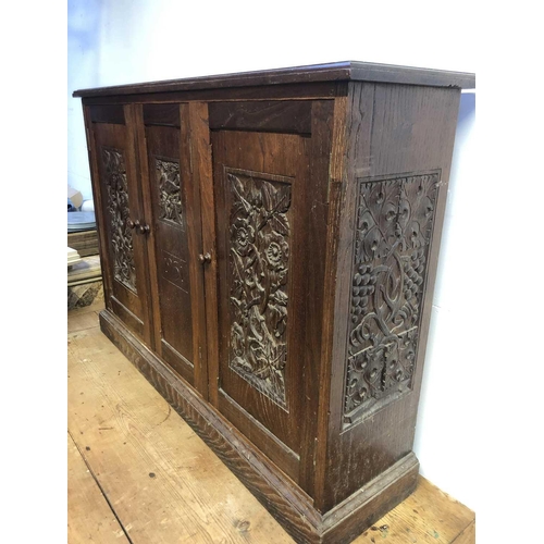 1804 - An Arts and Crafts oak cupboard, dated 1931, with three doors carved with hops, flowers and a bird, ... 