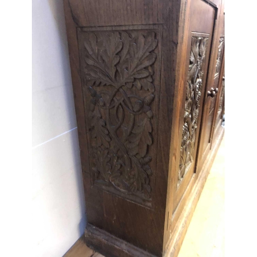 1804 - An Arts and Crafts oak cupboard, dated 1931, with three doors carved with hops, flowers and a bird, ... 