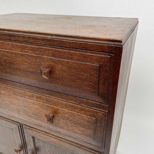 1811 - An Arts and Crafts oak bedroom cabinet, circa 1930, in the Cotswolds taste, fitted with two long dra... 