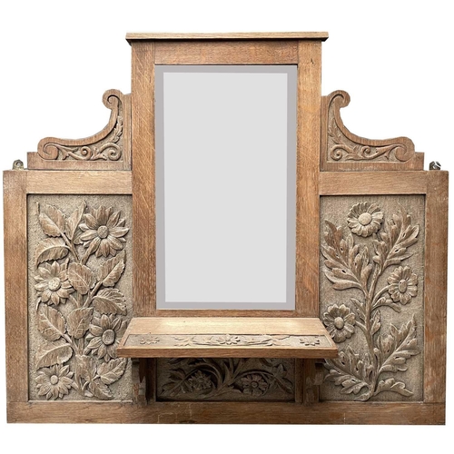 1812 - An Arts and Crafts oak hall mirror, with sunflower carved decoration and a single shelf, height 86cm... 