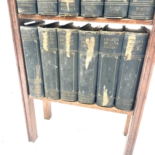 1825 - An oak narrow bookcase, early 20th century, containing 18 volumes of the Charles Dickens library, he... 