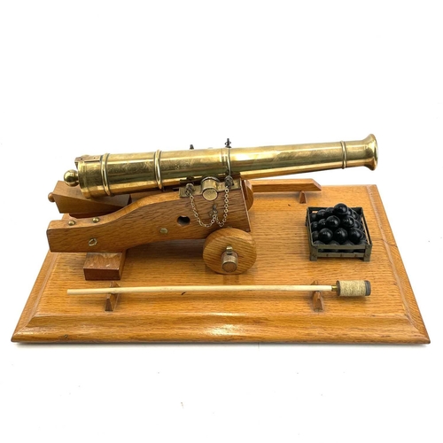 200 - A model brass cannon, mid 20th century, with oak carriage and base mounted with cannon balls etc, he... 