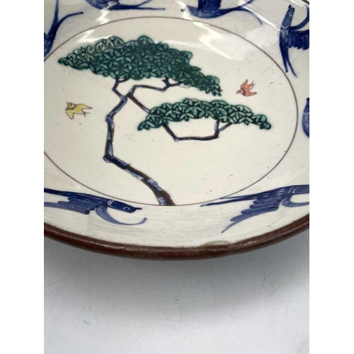 890 - An Alan Brough studio pottery dish, the centre decorated with a tree and birds, within a bird decora... 