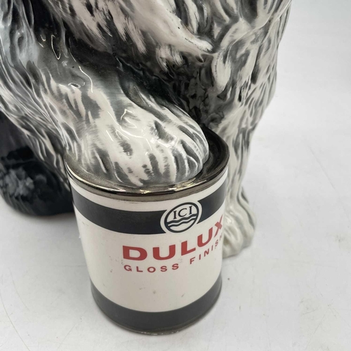 895 - A Beswick fireside advertising figure of the Dulux dog, with its front paw resting on a tin of paint... 