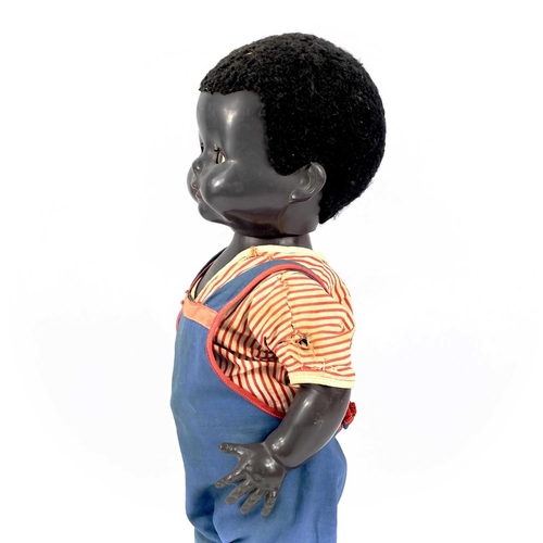 757 - A Black Celluloid Mechanical Walking, Closing Eyes Doll. Height 52cm, dressed in dungarees and red a... 