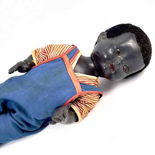 757 - A Black Celluloid Mechanical Walking, Closing Eyes Doll. Height 52cm, dressed in dungarees and red a... 