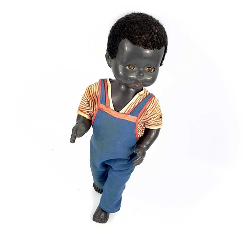 757 - A Black Celluloid Mechanical Walking, Closing Eyes Doll. Height 52cm, dressed in dungarees and red a... 