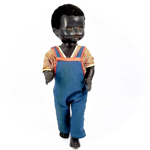 757 - A Black Celluloid Mechanical Walking, Closing Eyes Doll. Height 52cm, dressed in dungarees and red a... 