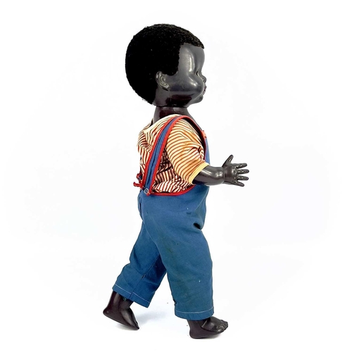 757 - A Black Celluloid Mechanical Walking, Closing Eyes Doll. Height 52cm, dressed in dungarees and red a... 