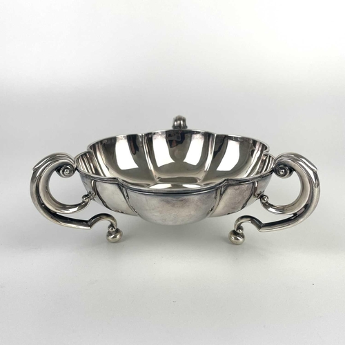 50 - An Edwardian silver lobed triple handled dish by Mappin & Webb. With flying scroll handles on ball f... 