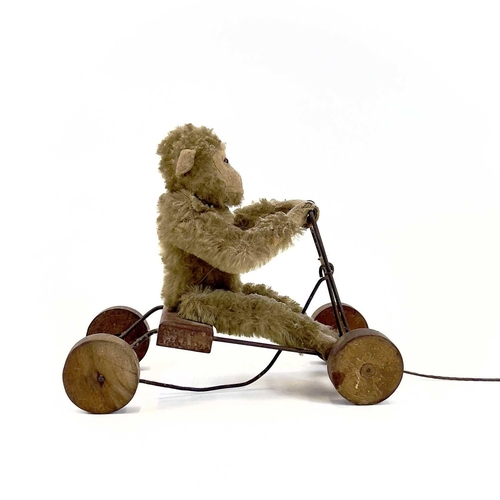 13 - A 1930s plush monkey on a cart probably Steiff. With wrought iron frame and wood seat and wheels, le... 