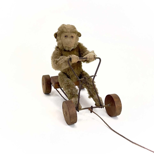 13 - A 1930s plush monkey on a cart probably Steiff. With wrought iron frame and wood seat and wheels, le... 