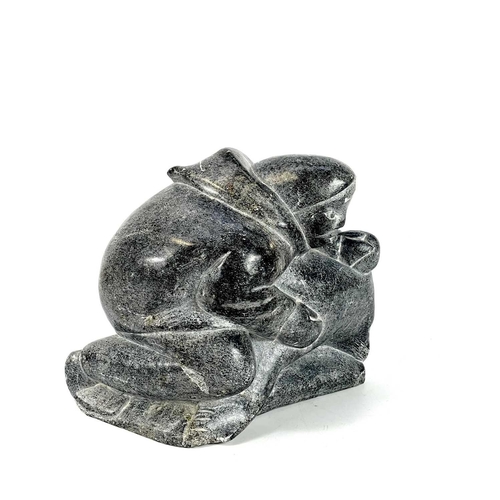 132 - A 20th century Inuit carved soapstone sculpture. Of a man holding a seal, having incised signature S... 