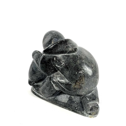 132 - A 20th century Inuit carved soapstone sculpture. Of a man holding a seal, having incised signature S... 