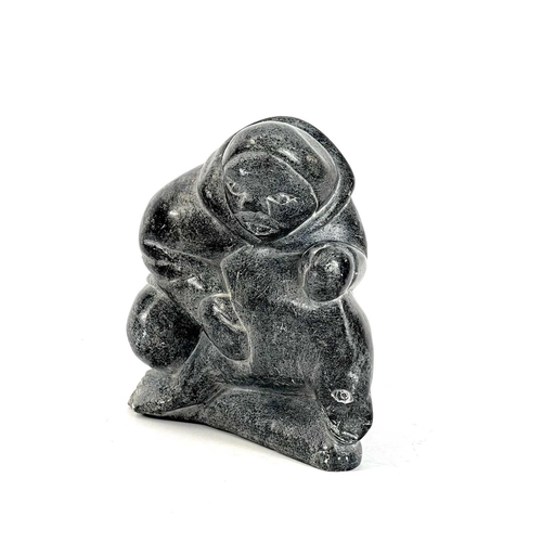 132 - A 20th century Inuit carved soapstone sculpture. Of a man holding a seal, having incised signature S... 