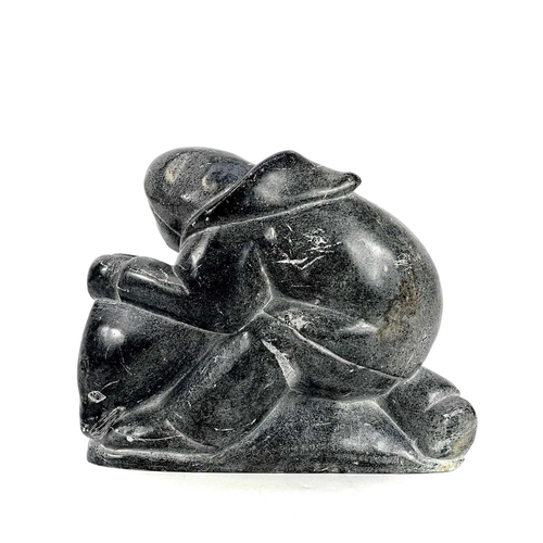 132 - A 20th century Inuit carved soapstone sculpture. Of a man holding a seal, having incised signature S... 