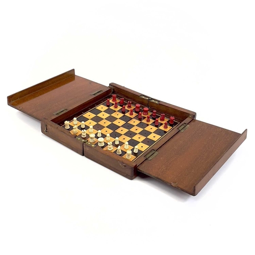 14 - A mahogany folding travel chess set. Circa 1900, fitted with red stained and natural bone pieces, wi... 