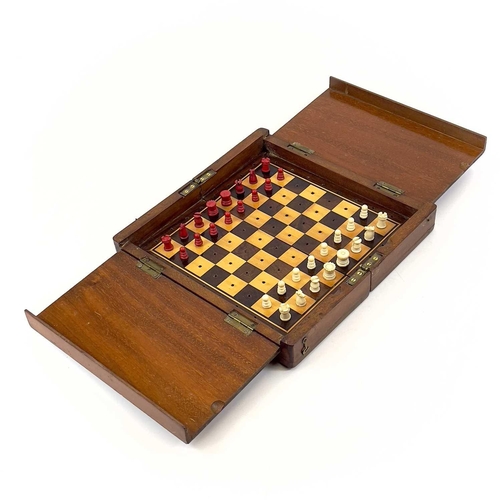 14 - A mahogany folding travel chess set. Circa 1900, fitted with red stained and natural bone pieces, wi... 