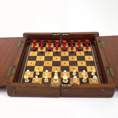 14 - A mahogany folding travel chess set. Circa 1900, fitted with red stained and natural bone pieces, wi... 