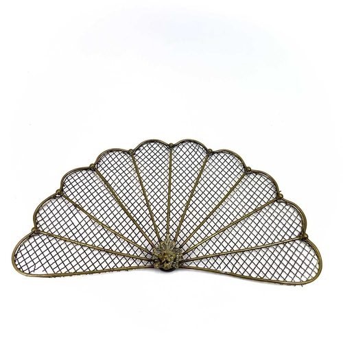 154 - A victorian brass fan shape spark guard. Centering a lion mask, the mesh with rod supports, height 3... 