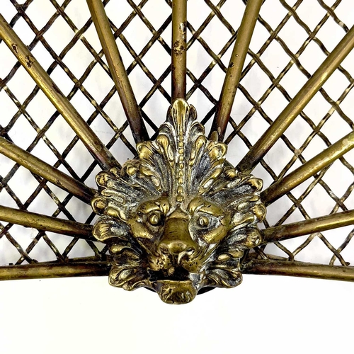 154 - A victorian brass fan shape spark guard. Centering a lion mask, the mesh with rod supports, height 3... 