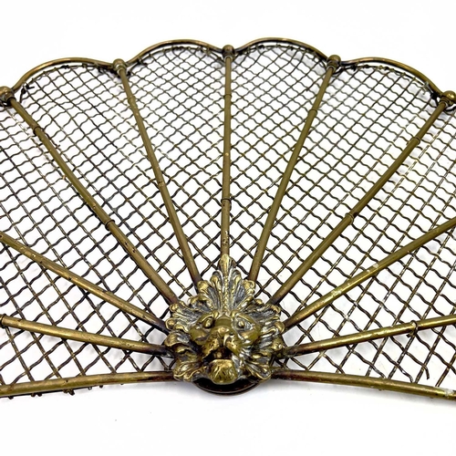 154 - A victorian brass fan shape spark guard. Centering a lion mask, the mesh with rod supports, height 3... 